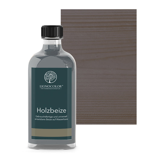 Holzbeize Grau in der Glasflasche mit gebeiztem Holz im Hintergrund.