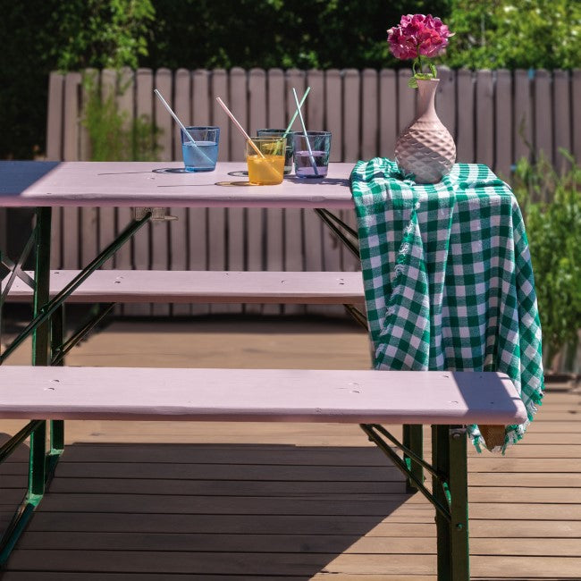 Auf der Terrasse steht eine Bierzeltgarnitur, die außen in einem hellen Violett namens „Seattle“ gestrichen wurde.
