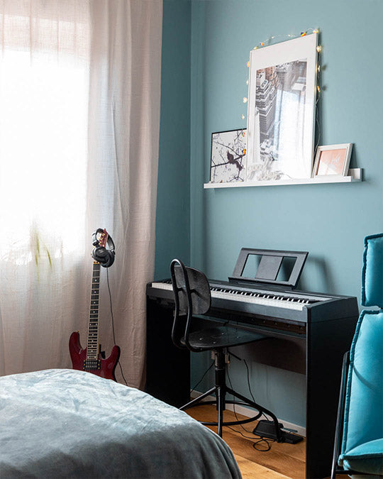 Wand im Kinderzimmer in einem gräulichen Blau mit Keyboard und Gitarre davor.